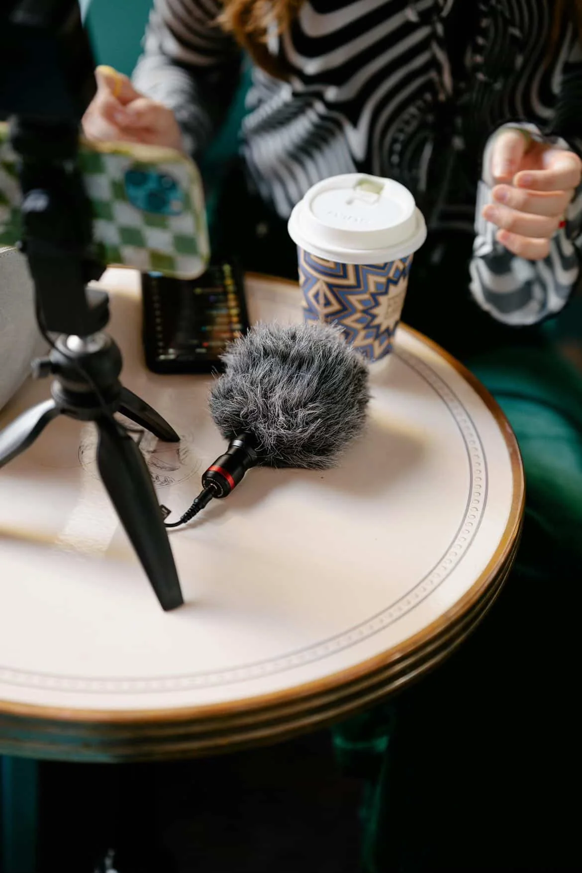 Close-up of audio recording equipment, microphone, and smartphone on a table during a confidential interview or investigative discussion.
